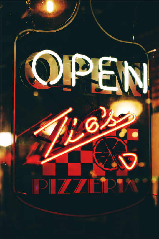 pizzeria employee holding a pizza in the kitchen